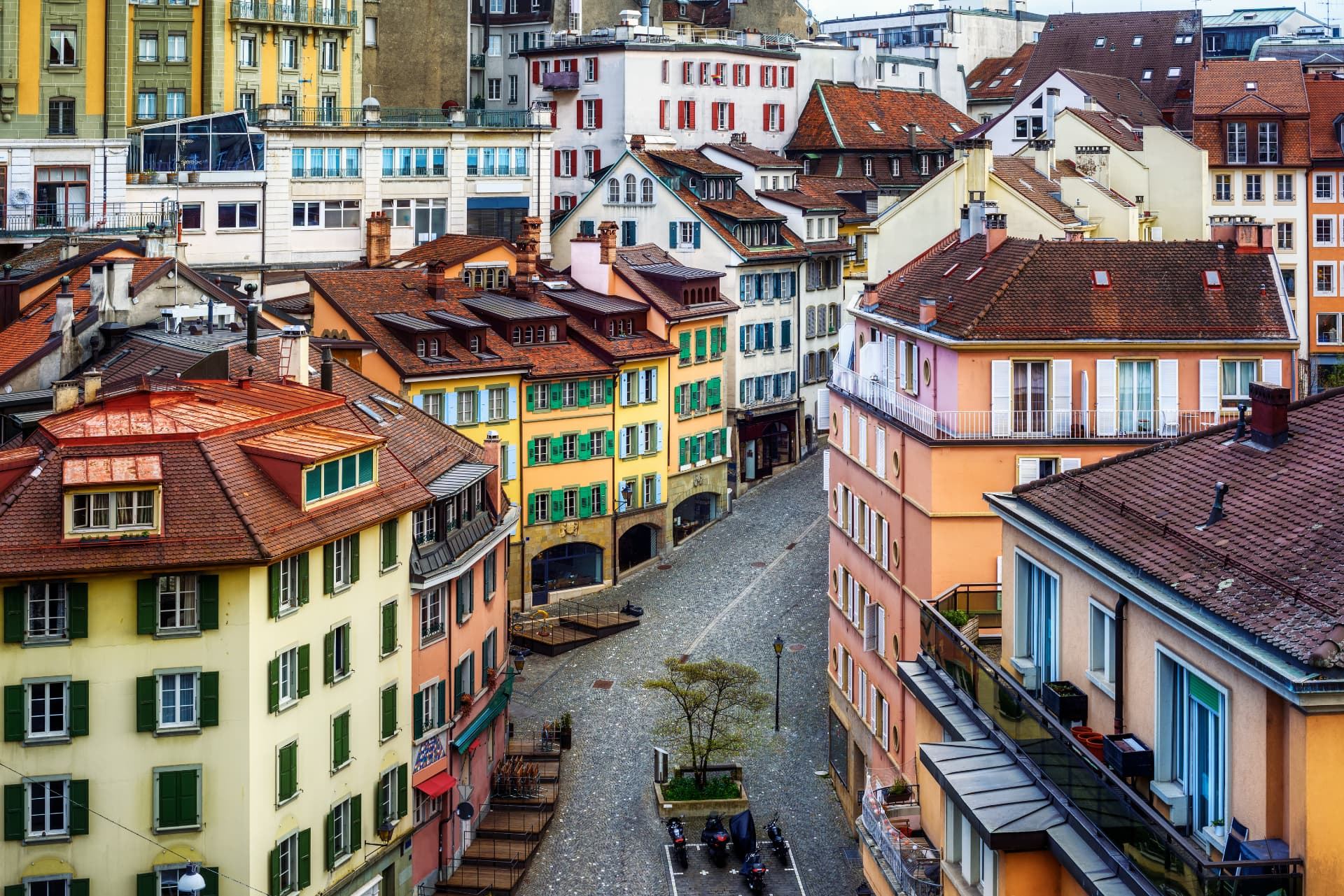 Vue en plongée d'une ruelle pavée bordée d'immeubles anciens aux volets colorés