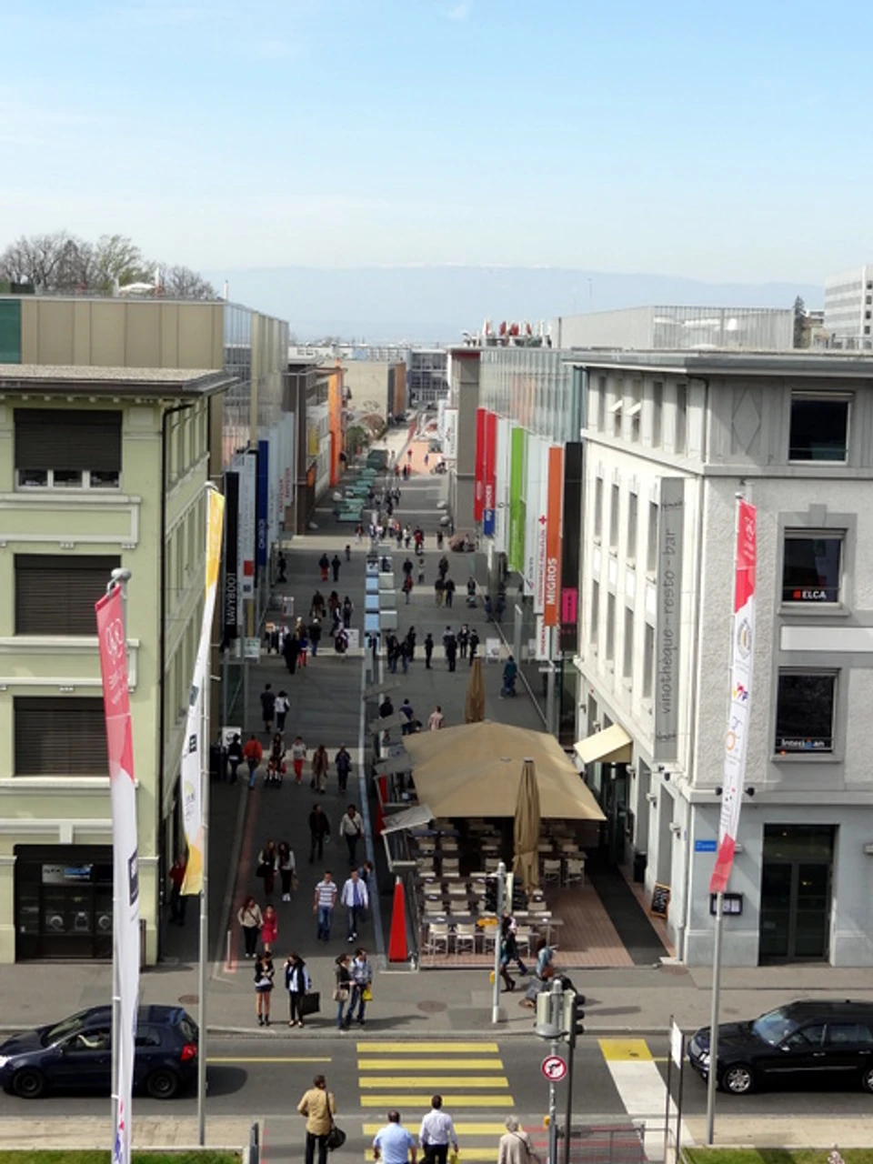 Rue piétonne vue en plongée, passants, terrasses et immeubles de part et d’autre