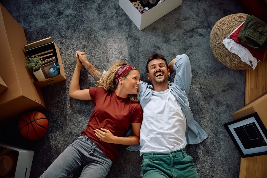 Couple souriant assis au milieu de ses cartons de déménagement