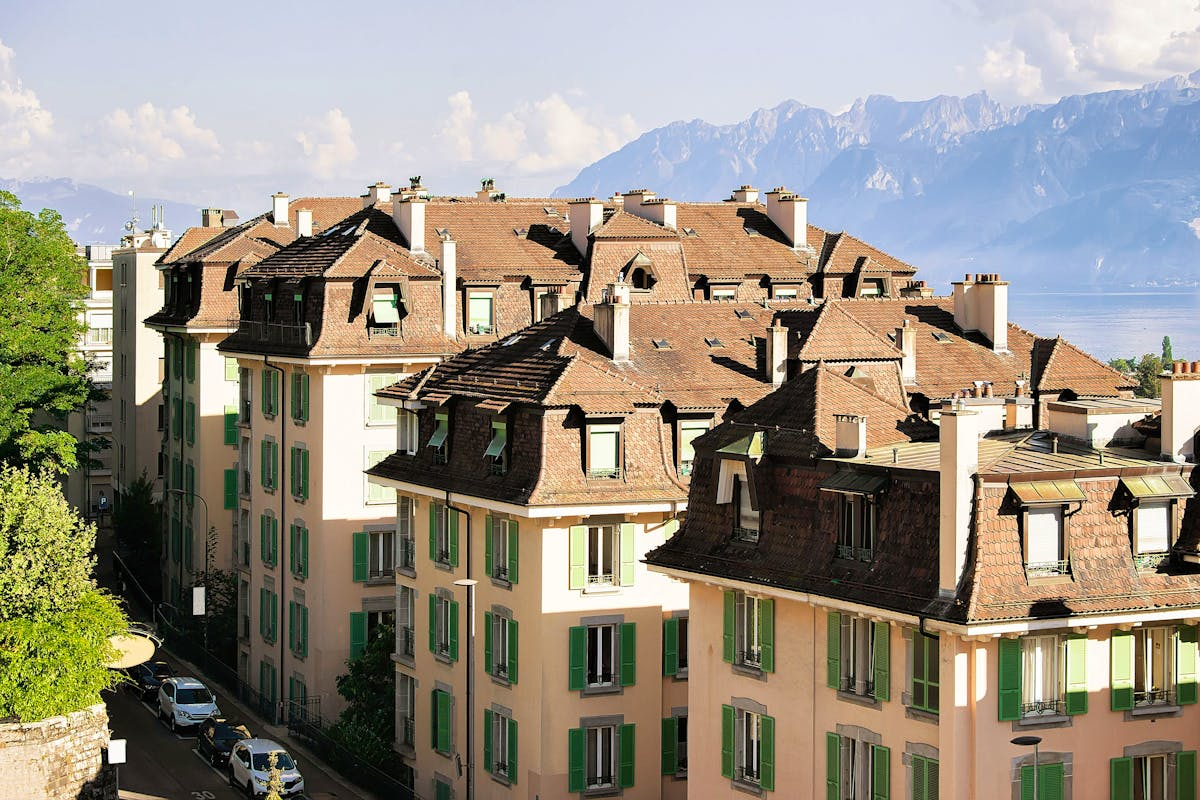 Immeubles d’habitation aux toits de tuiles, avec le lac Léman et les Alpes en arrière-plan