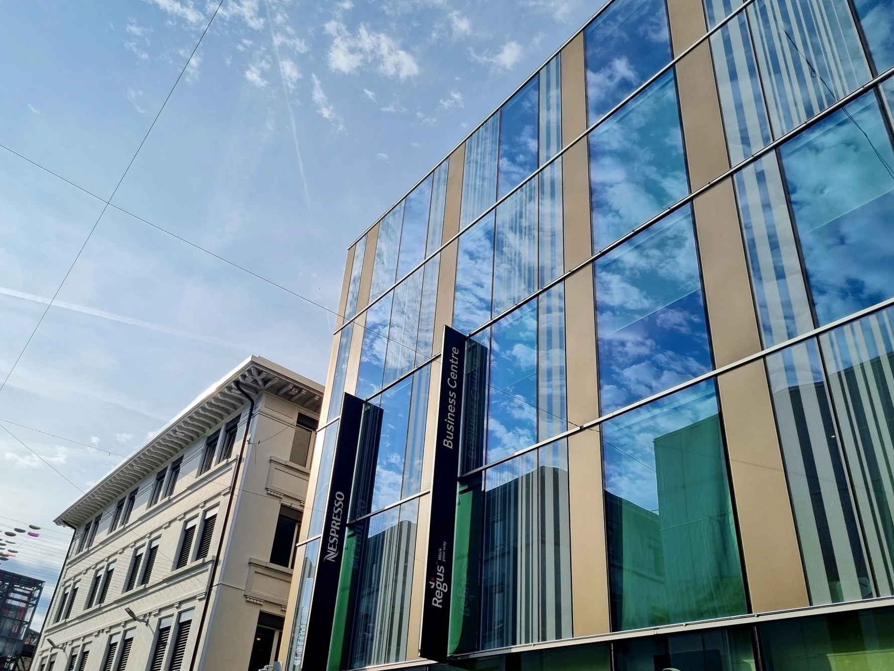 Façade vitrée d’un immeuble de bureaux avec enseignes, vue depuis la rue